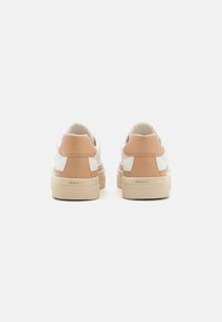 Paire de baskets blanches et beiges vues de dos avec une semelle beige et le logo "GANT" sur le talon.