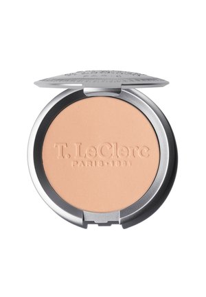 Polvere compatta con una texture liscia e cremosa in un delicato colore pesca, racchiusa in un elegante astuccio rotondo argentato con il nome del marchio impresso sulla superficie.