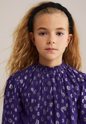 Violeta kleita ar sudraba leopardu plankumiem, gurnu dizains, augsts smocks kakls un pūkains piedurknes. Valkāta melna pītā galvassega.