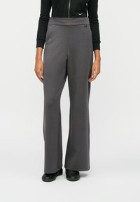 Γκρι παντελόνια σε φαρδιά γραμμή, κατασκευασμένα από μαλακό ύφασμα, με ψηλή μέση, πλαϊνές τσέπες και λεία υφή. Συνδυασμένα με μαύρα παπούτσια.