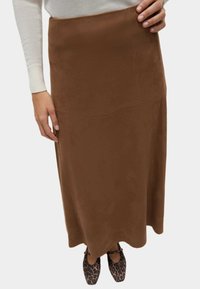 Falda maxi de ante marrón con una textura suave y detalles de costura. Combinada con zapatos de estampado de leopardo negro y marrón para crear contraste.