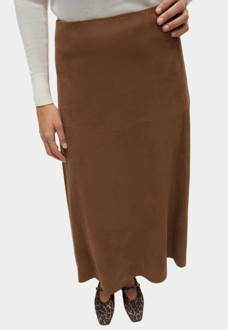 Falda maxi de ante marrón con una textura suave y detalles de costura. Combinada con zapatos de estampado de leopardo negro y marrón para crear contraste.