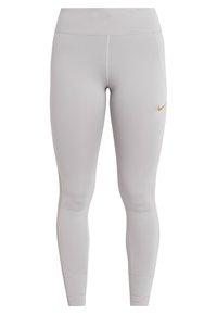 Jasnoszare legginsy sportowe wykonane z gładkiego, elastycznego materiału. Posiadają złote logo Nike na górnej prawej udzie oraz przeszycia.
