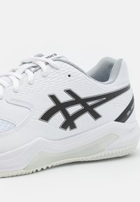 Pantofii sport albi au un upper texturat cu accente gri, branding negru și o talpă amortizată pentru suport și stabilitate.