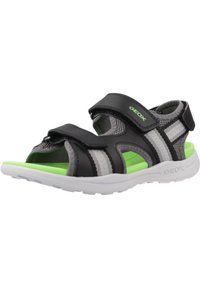 Sandalias negras y grises con correas ajustables, malla transpirable y una plantilla verde. Presenta una suela de goma blanca con agarre texturizado.