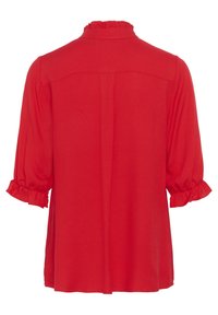 Blusa rossa con colletto e polsini arricciati, maniche a tre quarti e taglio dritto. Tessuto morbido con una superficie liscia.