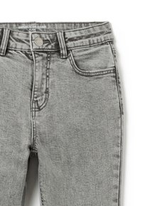 Jeans de mezclilla gris con corte acampanado, que presentan un cierre de botón, bolsillos cosidos y un acabado suave y texturizado.