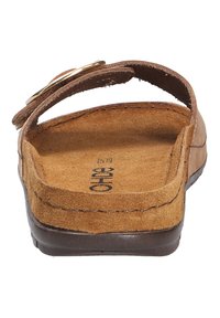 Brun mockaläder sandal med en bred rem och cirkulär metallisk detalj, med en vadderad sula och sydda detaljer längs kanterna.