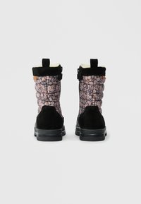 Par de botins de inverno acolchoados pretos e florais com solas pretas, vistos de trás num fundo simples.