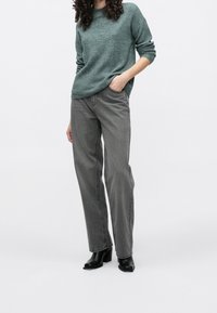 Grijze geribbelde trui, gecombineerd met lichtgrijze rechte jeans en zwarte enkellaarsjes. Eenvoudig, casual ontwerp met een ontspannen pasvorm.