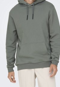 Sweat à capuche vert olive en tissu mélangé coton, doté d'une poche kangourou à l'avant, de cordons ajustables et de côtes aux poignets et à l'ourlet.