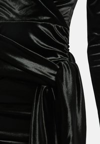 Schwarzes Satinkleid mit Rüschen-Design und gebundenem Knotendetail an der Taille. Verfügt über eine glatte, glänzende Textur und lange Ärmel.