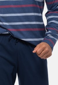 Camicia a maniche lunghe da uomo con righe orizzontali blu navy, bianco e bordeaux; pantaloni casual in blu navy uniforme; morbida texture di cotone.