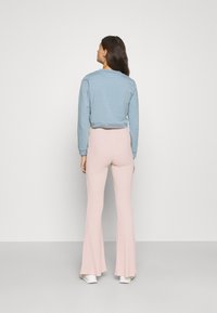 Sweatshirt cropped azul claro com mangas longas combinado com calças rosa largas. O material parece suave e elástico. Design simplista.