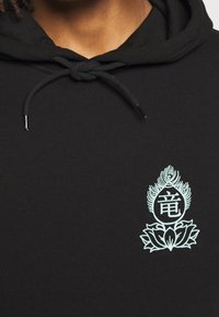 Czarna bluza z kapturem ze sznurkiem, z turkusowym graficznym wzorem stylizowanego motywu lotosu i smoka na obszarze klatki piersiowej.