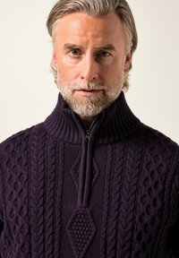 Lila gestrickter Pullover mit hohem Kragen, Reißverschluss und Zopfmuster mit diamantförmigen Akzenten. Strukturiertes Material mit dicker Rippung.