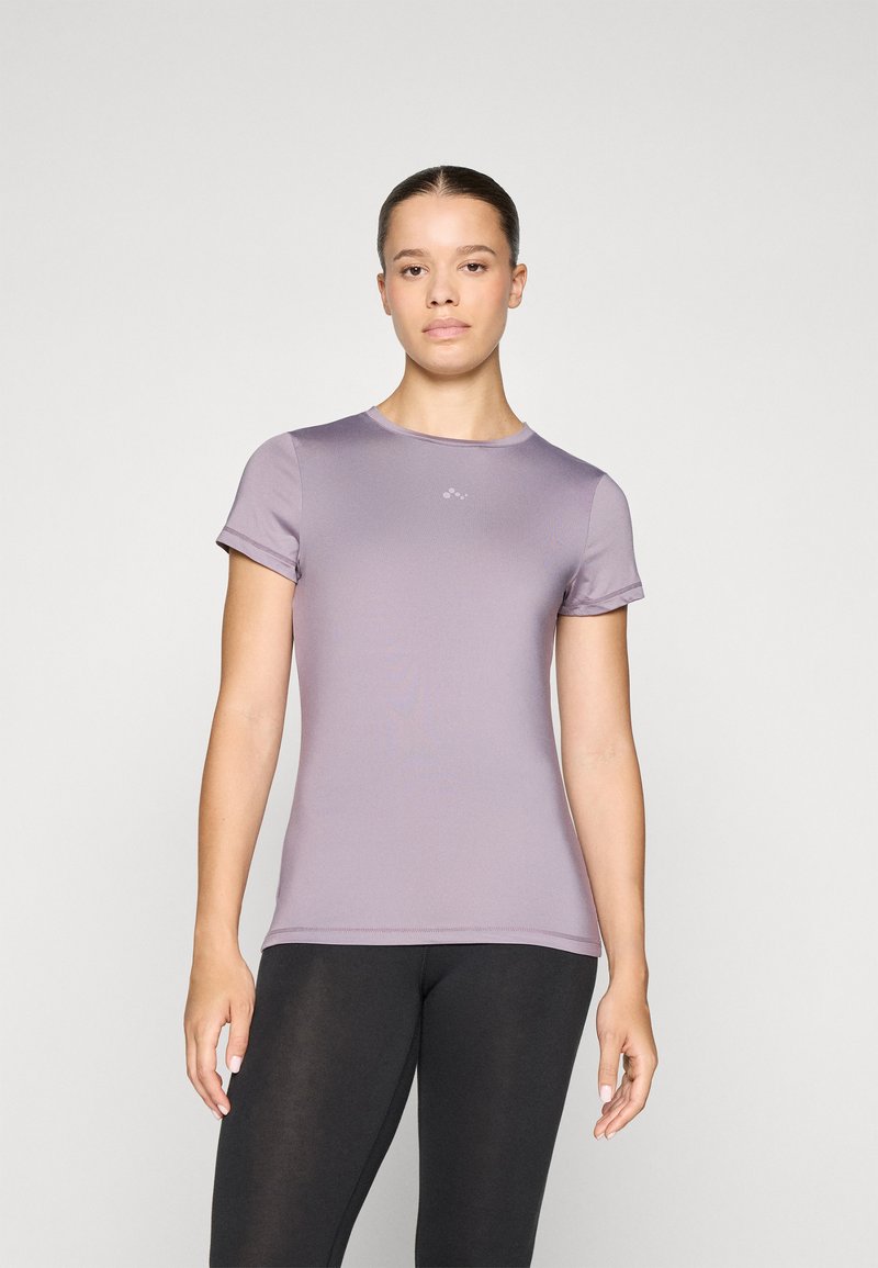 Short-sleeved, fitted t-shirt in light purple fabric, featuring a round neckline and subtle logo detail on the chest, paired with black leggings.