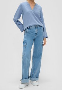 Blusa a maniche lunghe azzurro chiaro con scollatura a V abbinata a jeans cargo azzurro chiaro a vestibilità larga con tasche laterali e risvolti.