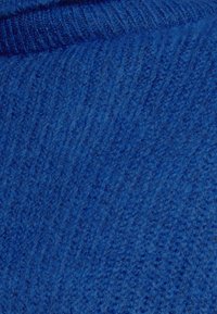 Nahaufnahme von blauer Strickware, die die detaillierte Rippentextur und weiche, flauschige Fasern zeigt.