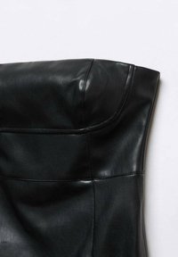 Gros plan d'un corset noir en cuir sans bretelles montrant les détails des coutures et la texture lisse sur fond blanc.