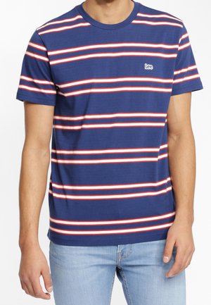 Granatowy T-shirt z krótkim rękawem, z poziomymi białymi i czerwonymi paskami oraz małym logo „Lee” na piersi, noszony z jasnoniebieskimi jeansami.