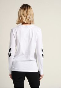 Witte longsleeve t-shirt met zwarte chevronpatronen op de mouwen, gemaakt van katoen, met een ronde hals en een losse pasvorm.