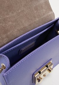 Bolso de cuero púrpura con superficie texturizada, interior de ante, herrajes en tono dorado y dos compartimentos con cierre magnético.