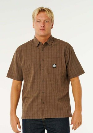 Kortærmet, brun skjorte med knapper og ternet mønster, enkelt brystlomme og en logo-badge på lommen. Knaplukning.