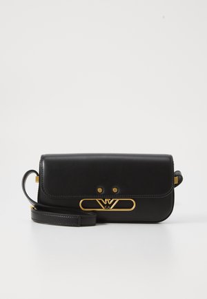 Bolso cruzado de cuero negro con un acento de logo en tono dorado, forma rectangular, cierre de solapa y correa ajustable. Textura suave, diseño minimalista.