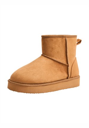 Stivale alla caviglia in suede color sabbia con punta arrotondata, cuciture tono su tono e suola in gomma testurizzata. Presenta un anello sul retro per una facile calzata.