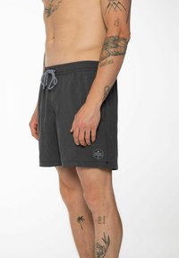 Pantaloni da bagno grigi con tessuto testurizzato, vita elastica, coulisse a contrasto e un'etichetta con logo sulla gamba sinistra.