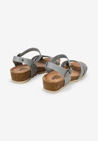 Sandalias de cuero gris con suelas de corcho, que cuentan con correas ajustables en el tobillo y una plantilla texturizada. El diseño de las correas proporciona un estilo abierto.