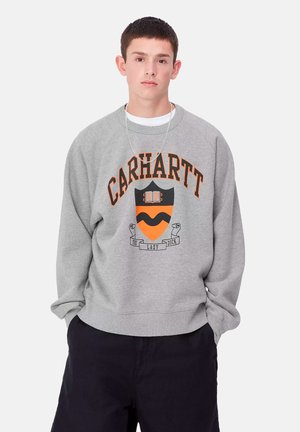 Felpa grigia con un collo arrotondato, caratterizzata dalla scritta "CARHARTT" in arancione e un design a scudo con un motivo arancione e nero.