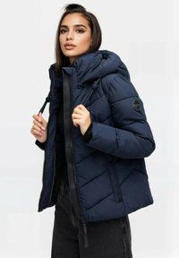 Granatowa kurtka puchowa z kapturem, bocznymi kieszeniami i wzorem w diamentową kratkę. Posiada zamek z chwostem oraz naszywkę z logo na rękawie.