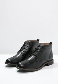 Botas de tobillo de cuero negro con detalles de brogue, acabado suave, puntera redonda y tacón bajo apilado. Diseño con cordones.
