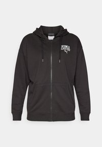 Sudadera con cremallera negra hecha de tela suave, con capucha ajustable, bolsillos tipo canguro y un logo bordado blanco en el pecho.
