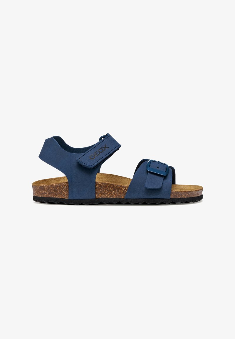 Sandale bleue à bout ouvert avec boucle réglable et brides en velcro, semelle intérieure en liège, semelle extérieure noire rainurée et logo Geox sur la bride de la cheville.