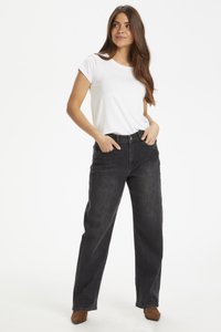 Zwarte wijde jeans met een hoge taille, vijf zakken en een koperen knoop, gecombineerd met een aansluitend wit T-shirt en bruine enkellaarsjes met hak.