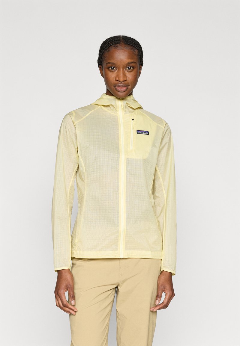 Ελαφρύ κίτρινο αντιανεμικό με κουκούλα, φερμουάρ μπροστά και μια μικρή τσέπη στο στήθος. Κατασκευασμένο από υλικό με υφή που επιτρέπει την αναπνοή του δέρματος.