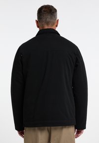 Černá bunda s stojáčkem, zapínáním na knoflíky a dlouhými rukávy. Materiál má hladkou texturu a rovný střih.