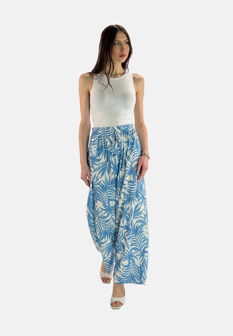 Vitt linne med en maxi kjol i blå och vit blommönster, med elastisk midja och flödande tygtextur, bärs med vita klackar.