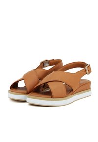 Sandali in pelle marrone con design a strap incrociati, punta aperta e cinturino alla caviglia regolabile. Suola a strati bianca e beige per un maggiore comfort.