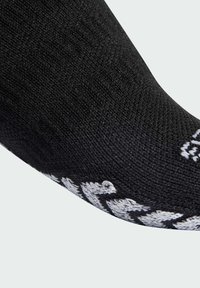 Calcetín negro con un diseño de punto texturizado, con acentos blancos y un puño con patrón. La vista en primer plano destaca el material y la forma.