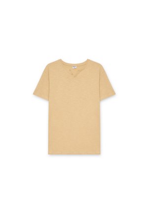 Camiseta beige de manga corta de algodón con cuello redondo y dos pequeños botones cerca del collar sobre un fondo blanco.