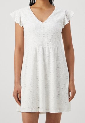 Mujer con un vestido blanco de manga corta y escote en V, con patrón de encaje de ojales y falda acampanada.