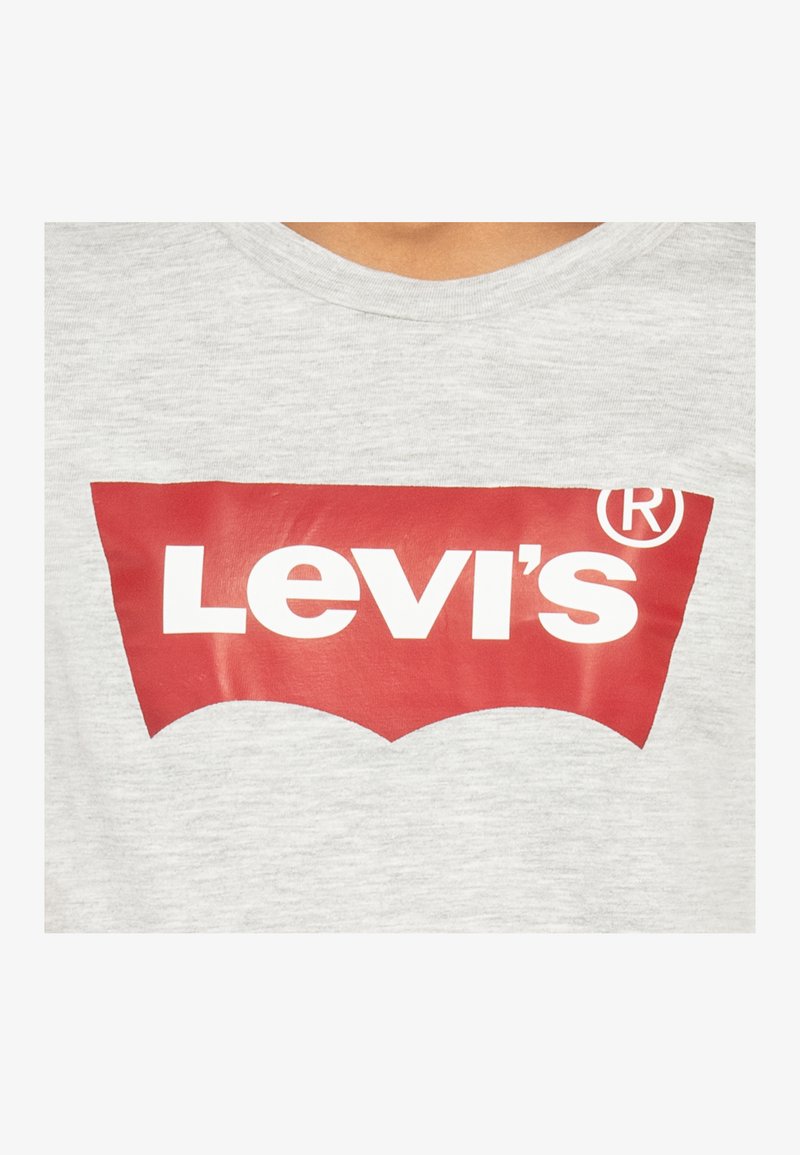 T-shirt en coton gris avec un col rond, arborant un logo Levi's rouge bien en vue avec du texte blanc sur le devant, mettant en avant le design emblématique de la marque.