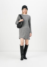 Gray long-sleeve dress with a slight A-line shape, worn with knee-high black leather boots and a slouchy black bag. Smooth texture throughout.