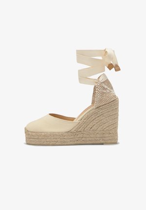 Beige canvas espadrille sleehak met een gevlochten jute plateau en enkelbandjes van dezelfde stof.