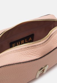 Růžová kožená taška se zlatým zipem. Vnitřek s hladkou podšívkou a malou kapsou na zip. Uvnitř viditelná značka značky.