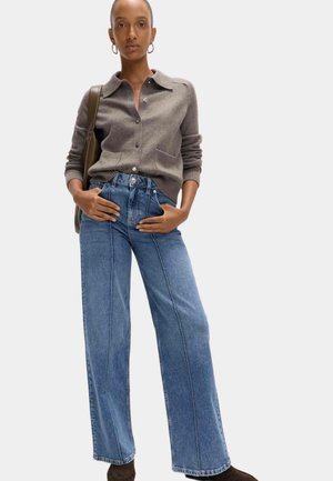 Grijze gebreide cardigan met een kraag en knopen, gecombineerd met hoog aangesloten, wijde blauwe denim jeans met contrasterende naden.